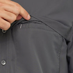 Close-up of a person opening hidden chest pocket on a dark gray outdoor button-up shirt.