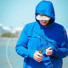 Person in a blue raincoat using fishing equipment with a blurred background