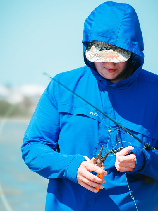 Person in a blue raincoat using fishing equipment with a blurred background