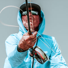 Person in a light blue hoodie holding a fishing rod with a gray background