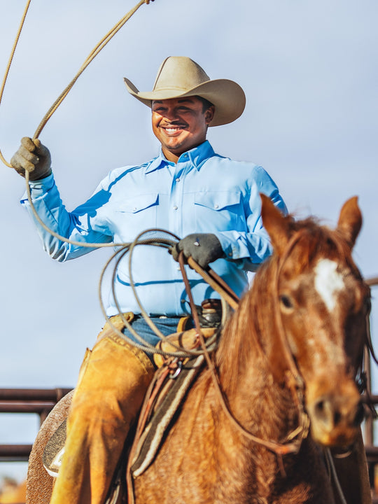 Man on horseback holding a lasso against a clear sky